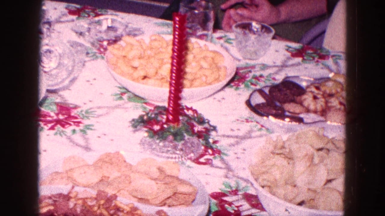 Holiday table with chips, crackers, cookies, glassware, and a red candle.