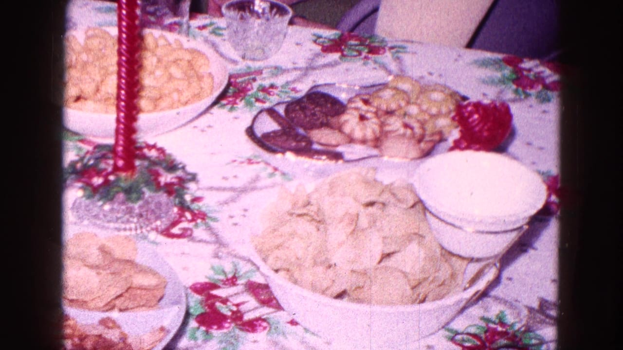 Snack table with a red candle, chips, cookies, crackers, and a white bowl.