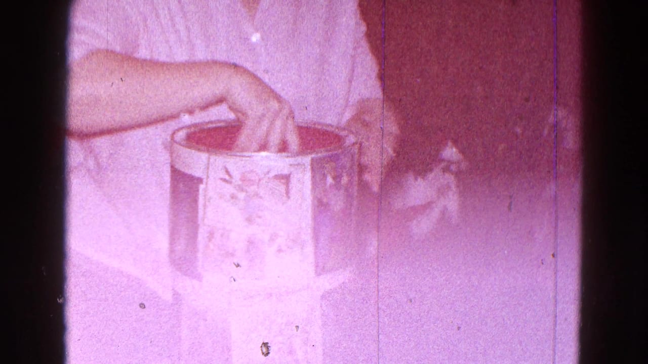 Hands reach into an open cylindrical box on a light surface.