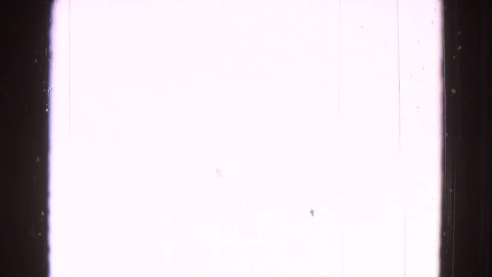 Mostly overexposed 8mm frame with visible scratches, dust, and dark film edge at the side.