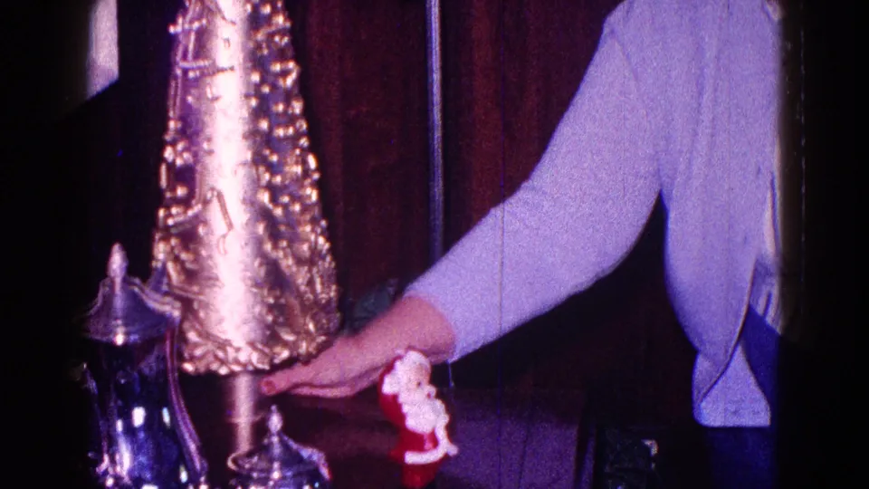 Close 1968 Minnesota home-movie view of a woman arranging a gold cone Christmas decoration in a private holiday interior.