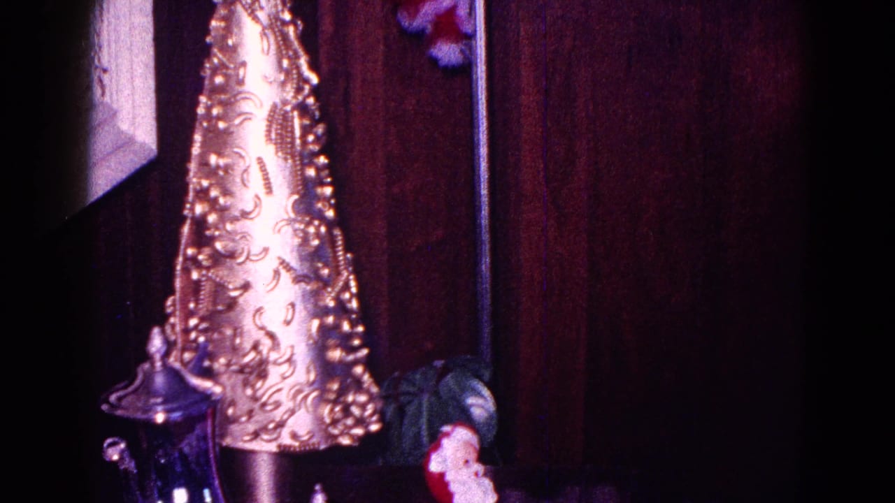 A gold tabletop Christmas tree ornament and small Santa figure appear in a wood-paneled Minnesota interior from 1968 footage.
