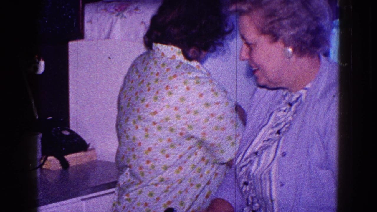 1968 Minnesota home-movie frame showing two women beside a white refrigerator and kitchen counter.