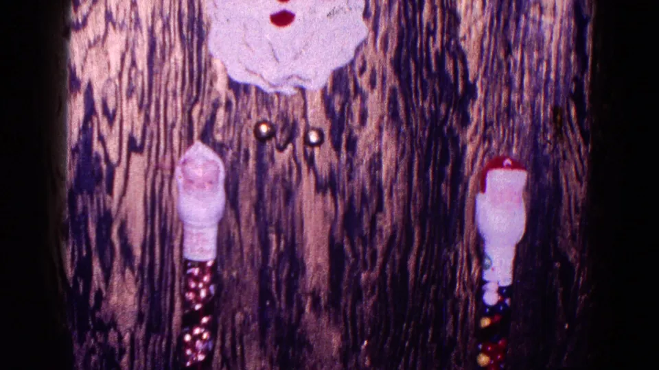 Close 1968 Minnesota home-movie view of small Santa Claus decorations on a wood-patterned surface, suggesting holiday decor.