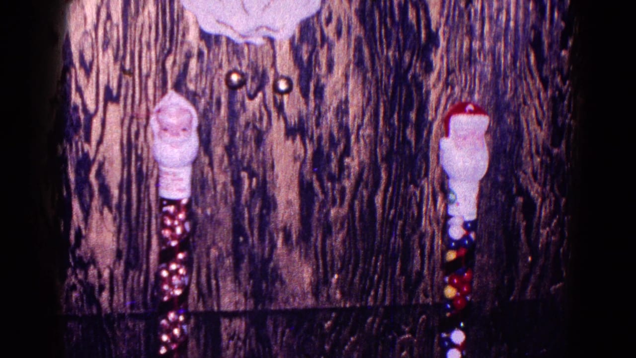 Two Santa-themed hanging decorations on wood paneling above a dark mantle edge.