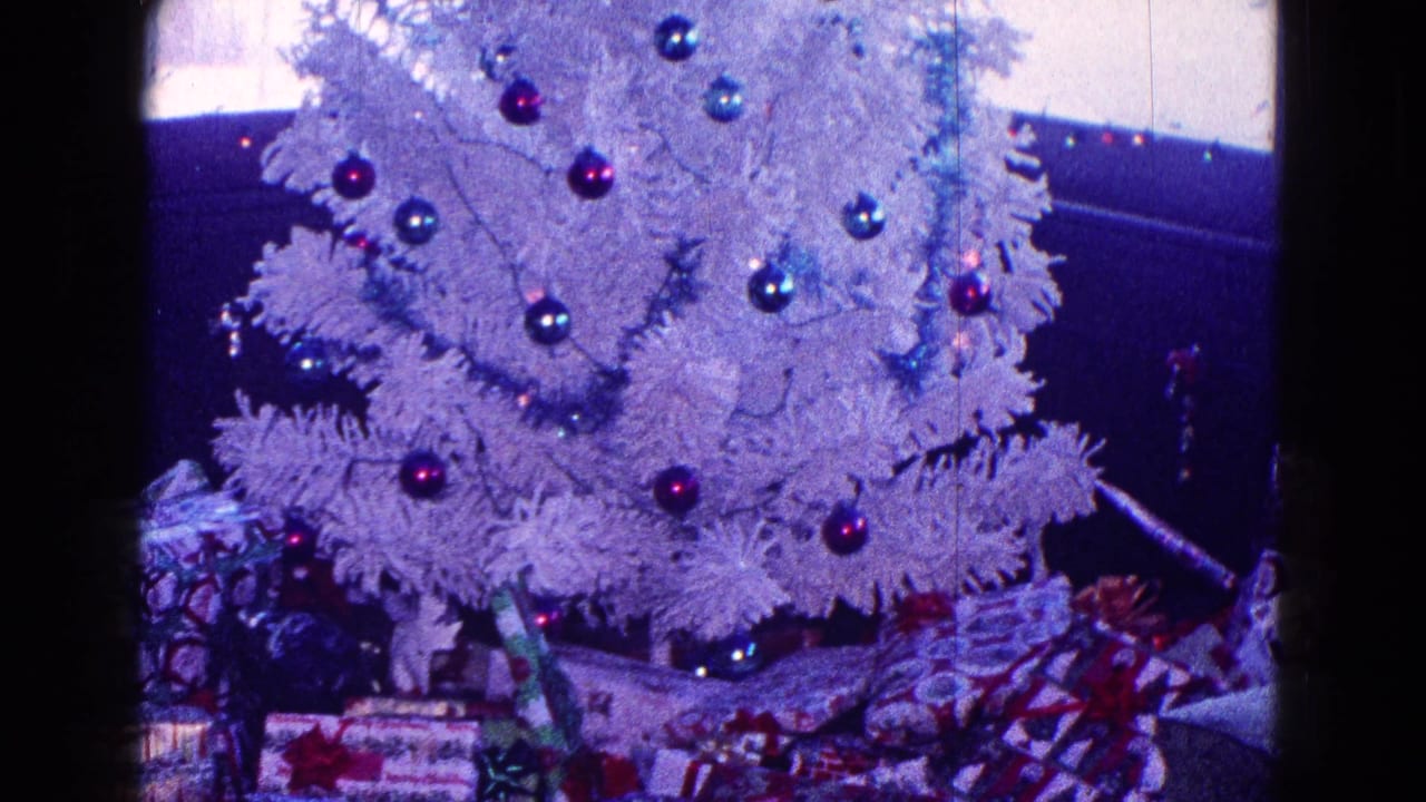 White Christmas tree with red and blue ornaments above wrapped presents.