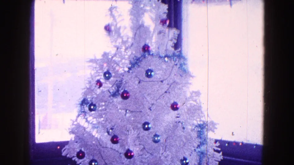 1968 Minnesota 8mm frame showing the upper part of a white artificial Christmas tree against daylight from a window.