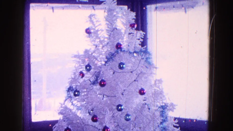 1968 Minnesota home-movie frame of a white artificial Christmas tree with ornaments near a daylight window.