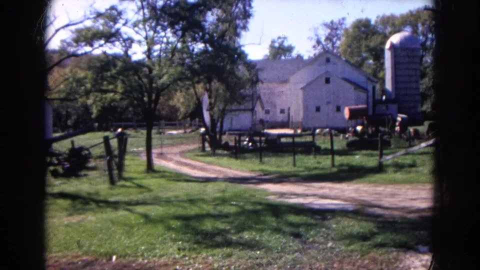 1968 Wauconda, Illinois frame showing a white barn, tall silo, dirt lane, trees, fencing, grass, and farm machinery.