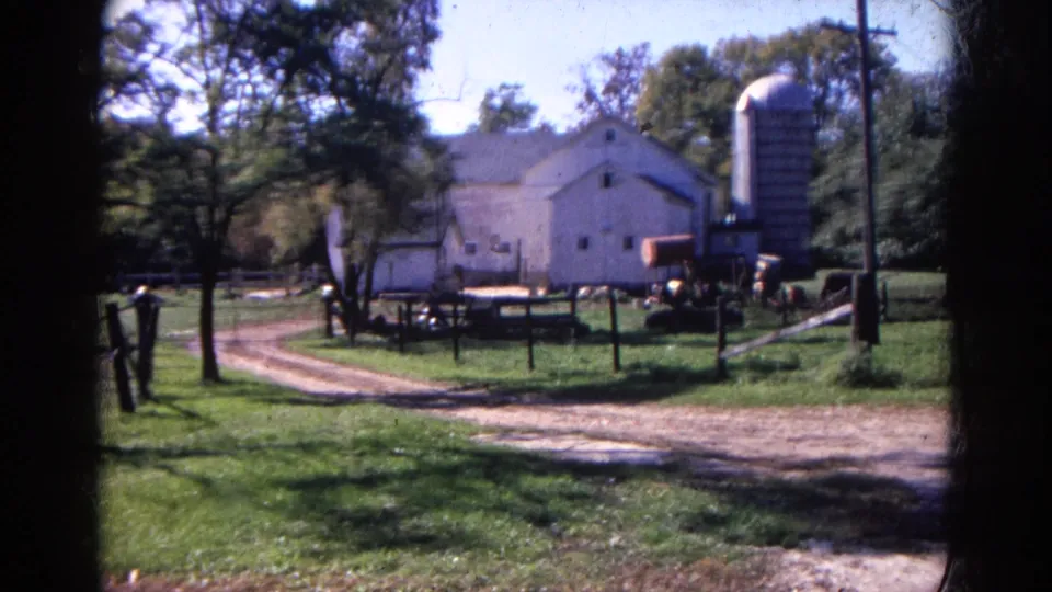 Final 1968 Wauconda farmstead frame with barn, silo, dirt road, utility pole, trees, fence rails, and equipment.