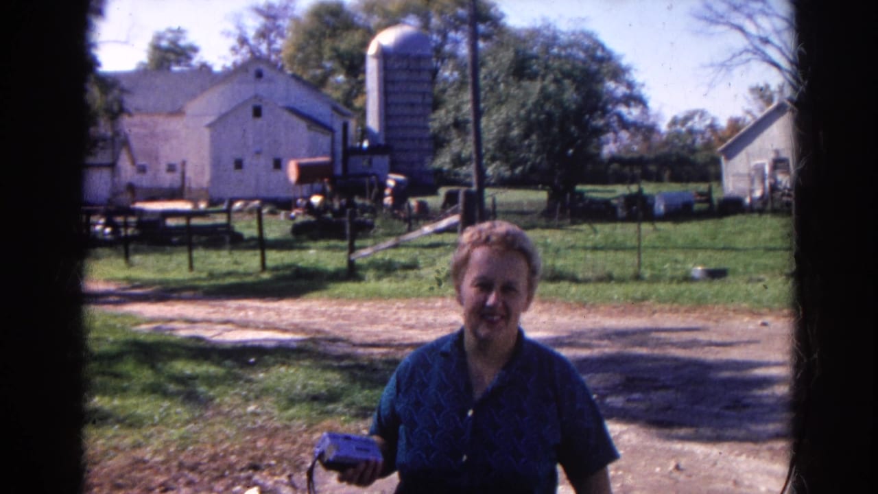 A smiling woman holds a small object while standing closer to the camera on a Wauconda farm in 1968.