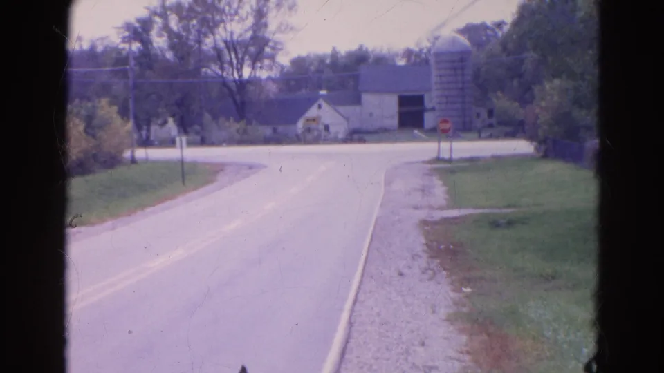 A Wauconda rural roadside in 1968 appears with a curving two-lane road, farmstead, silo, trees, and a red stop sign.
