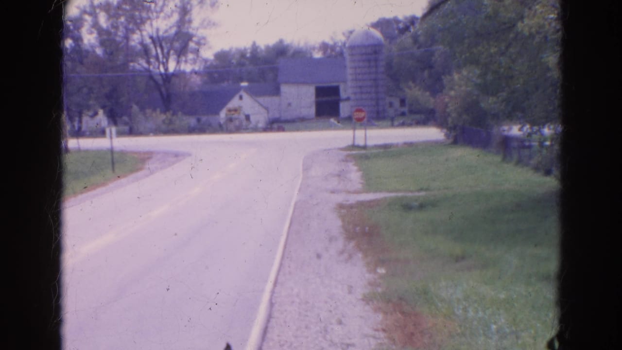 1968 Wauconda, Illinois 8mm frame showing a rural road, gravel shoulder, stop sign, barn, silo, and trees.