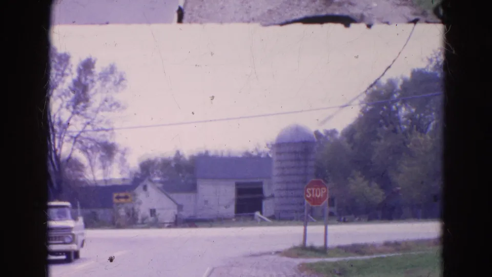 The pickup begins to leave the frame while the 1968 rural Illinois farm scene holds on the barn, silo, stop sign, road, and trees.