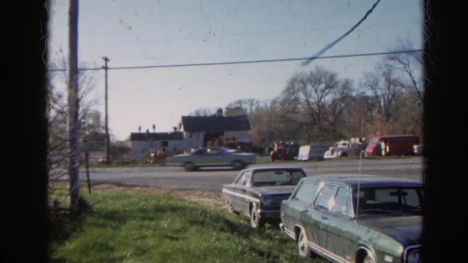 In the final Wauconda frame, a moving car crosses the road behind a parked station wagon and sedan near a barnhouse and background vehicles.