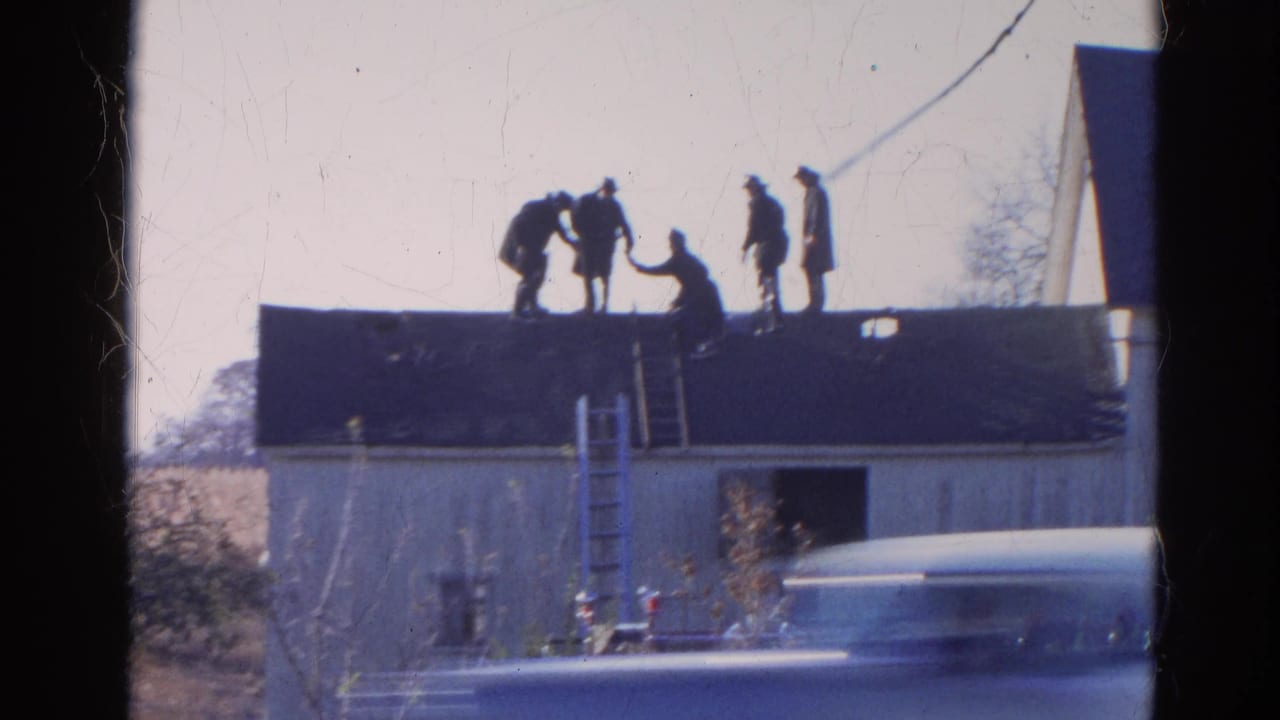 In Wauconda, Illinois, 1968 home-movie footage, firefighters work on the roof of a low building with ladders below.