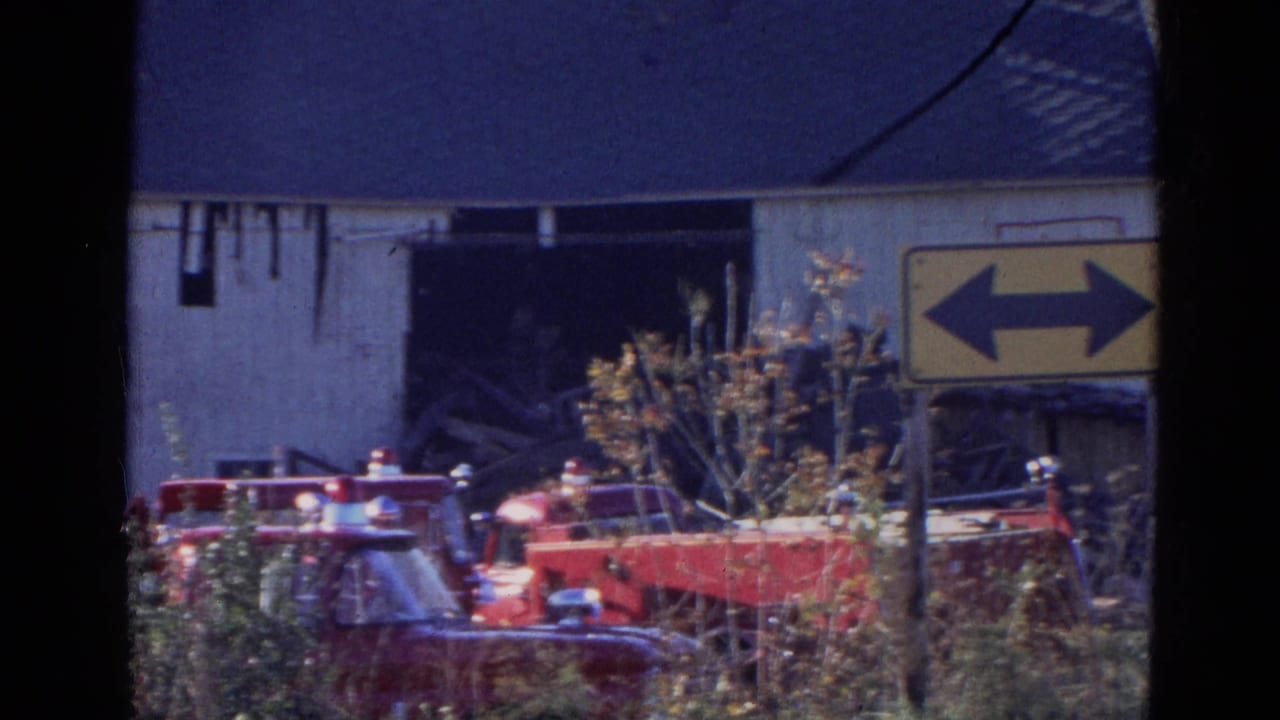 Red fire trucks sit near a damaged building with a yellow two-way arrow sign nearby.