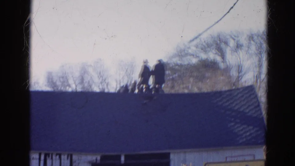 1968 Wauconda, Illinois frame with distant figures on a sloped roof, partly framed by film-strip borders.