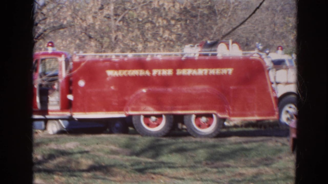 Red Wauconda Fire Department truck parked on grass beside bare trees.