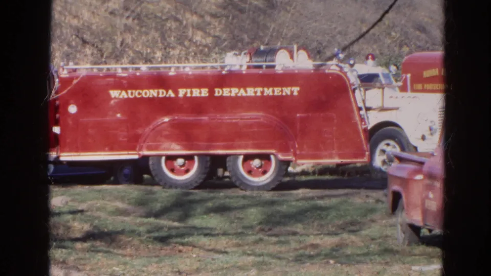 Close side view of the red Wauconda Fire Department truck, with a partial vehicle at the right edge of the 8mm frame.