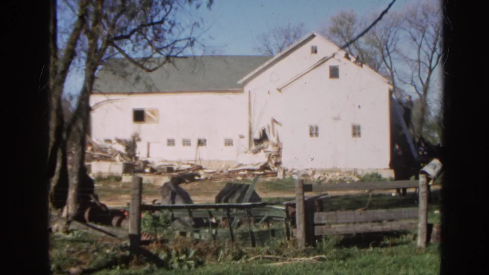 White rural barn in Wauconda, Illinois, with visible damage and debris in 1968 home-movie footage.