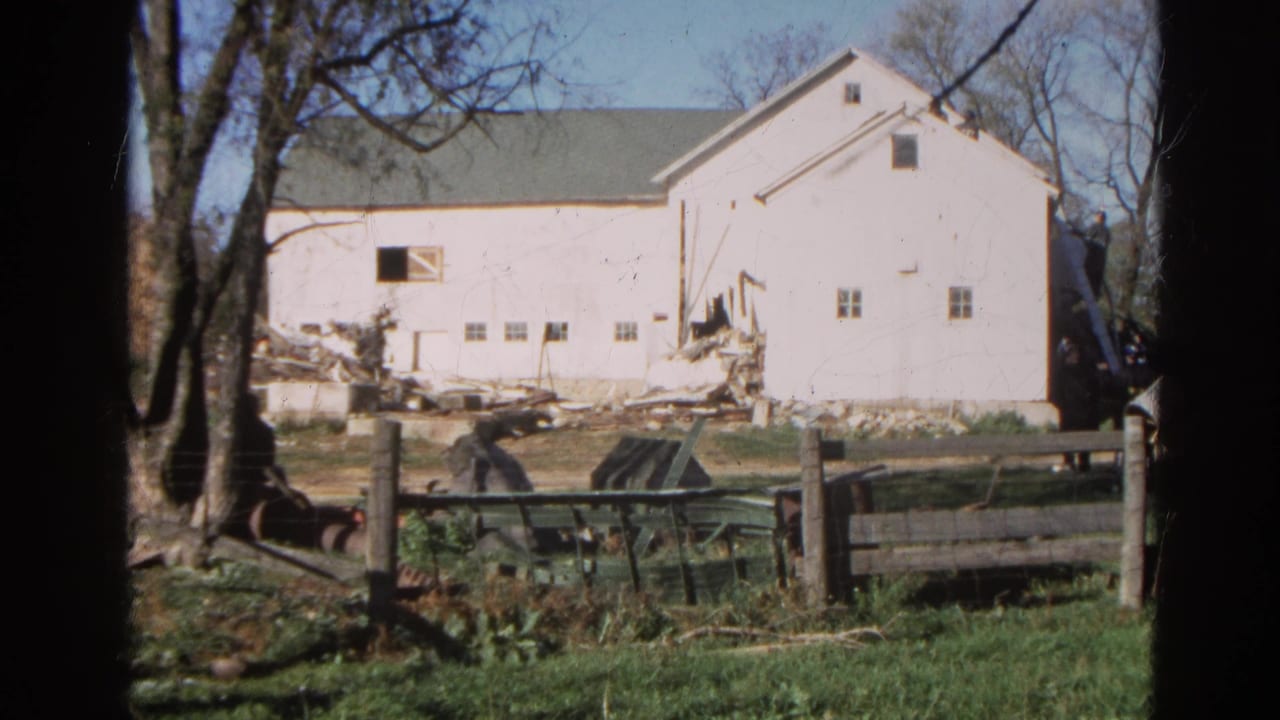 1968 Wauconda, Illinois 8mm frame showing a white barn under demolition or repair, with debris, fencing, grass, and bare trees.