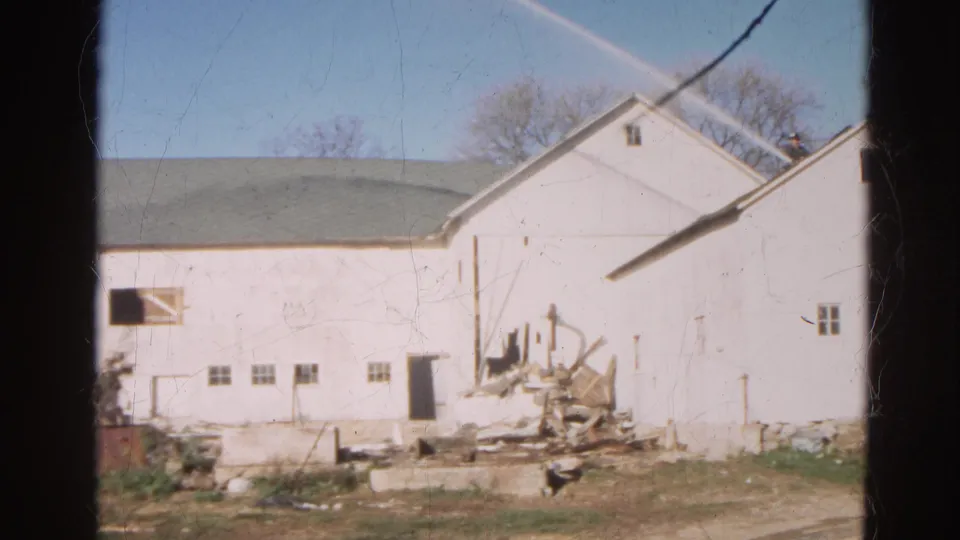 1968 Wauconda, Illinois frame of a white barn or farm building with a doorway, small windows, and demolition debris nearby.