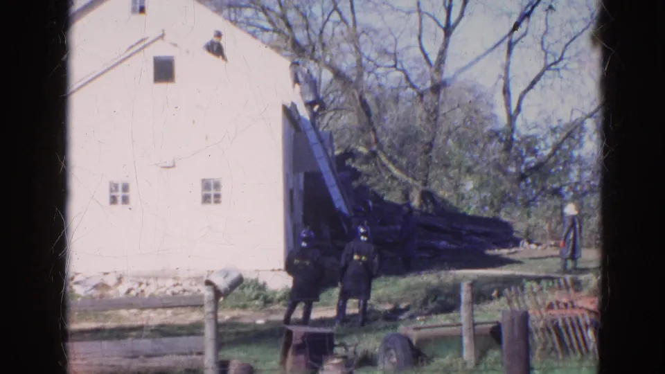 1968 Wauconda, Illinois home-movie frame of a white house, roof ladder, and uniformed adults standing in the yard.
