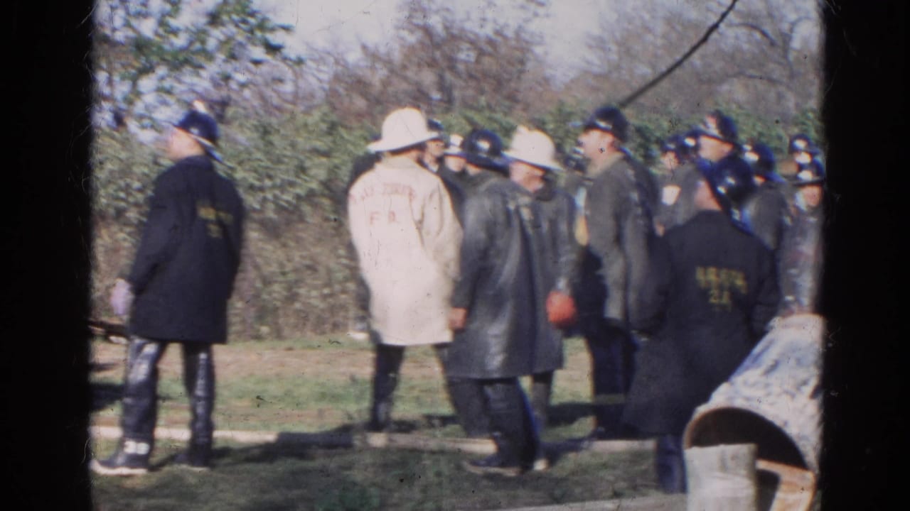 1968 Wauconda-area firefighters stand in an outdoor field, including a beige Lake Zurich F.D. coat and several dark helmets.