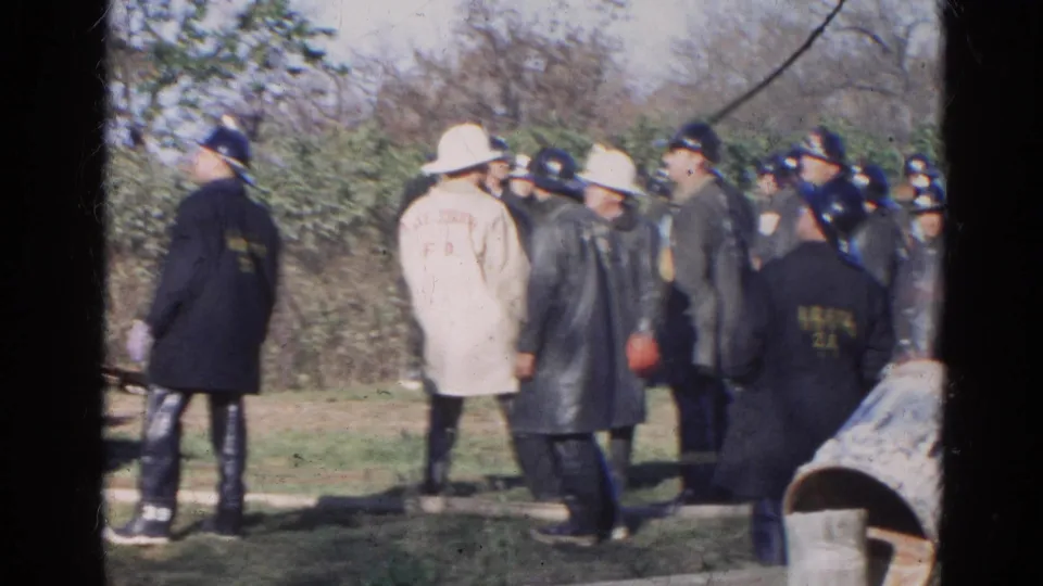 1968 Wauconda-area firefighters stand in an outdoor field, including a beige Lake Zurich F.D. coat and several dark helmets.