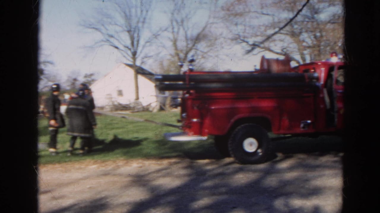 Red fire truck parked on a rural road with firefighters standing nearby.