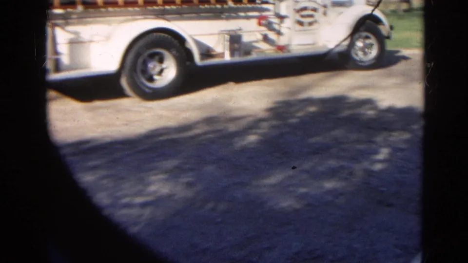 A white vehicle passes through the frame near the end of the 1968 home-movie clip, with pavement and shadows visible below.