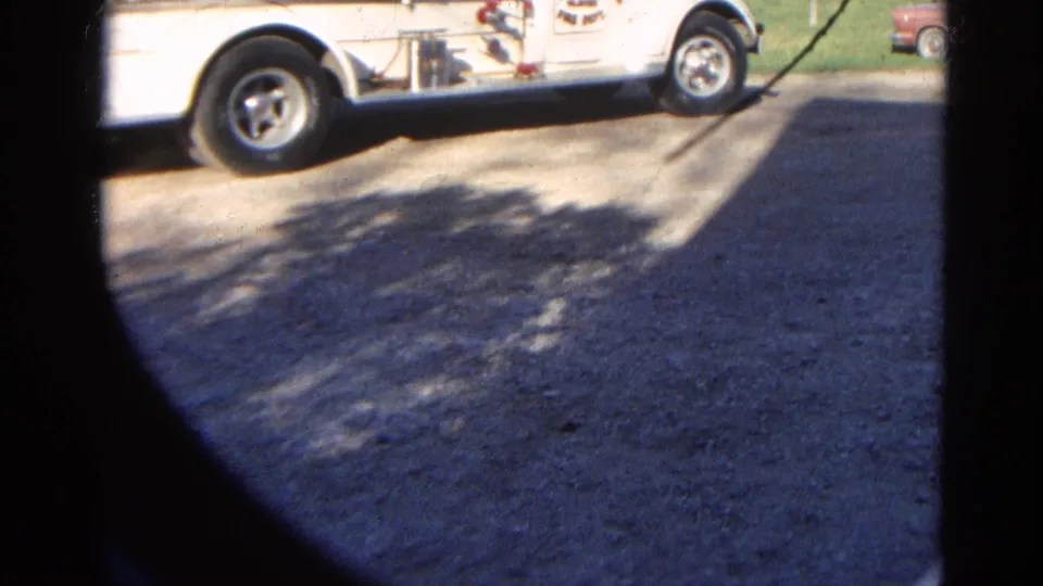 1968 8mm frame from Wauconda, Illinois showing the lower side of a white fire truck near a quiet paved area.