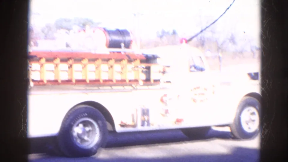 White Round Lake Fire Department-style truck appears in bright daylight with ladder rack and hose equipment visible.