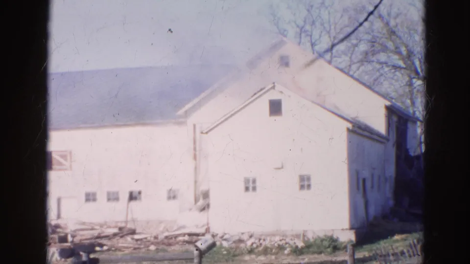 1968 Wauconda 8mm frame showing the farmhouse as faint smoke appears around the upper roofline and trees.