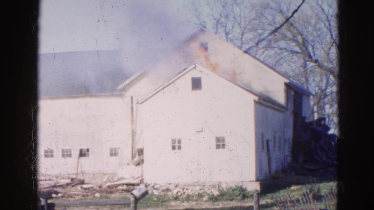 1968 Wauconda, Illinois 8mm frame showing a white barn with smoke along the roofline, bare trees behind it, and debris near the wall.