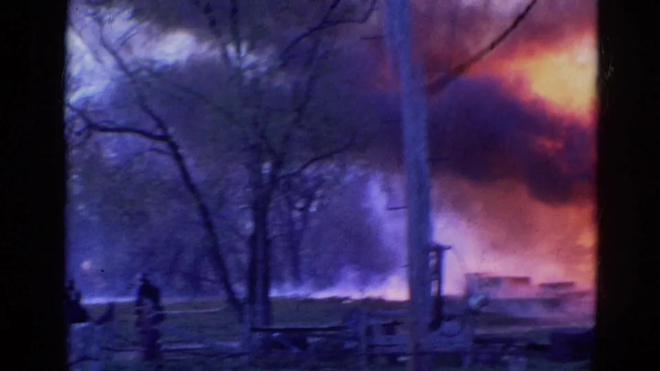 1968 Wauconda, Illinois frame showing smoke and flames through trees as firefighting water reaches the fire area.