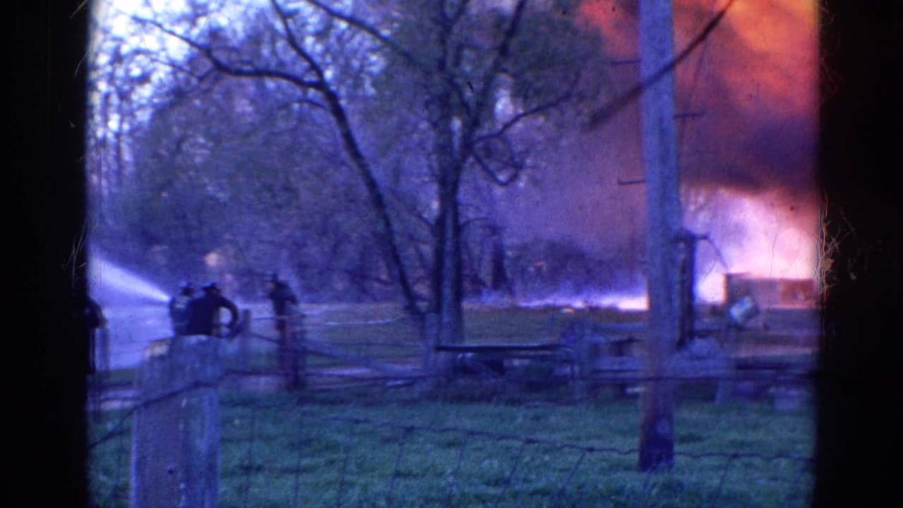 1968 Wauconda, Illinois 8mm frame showing firefighters aiming hoses at flames and smoke in a rural field.