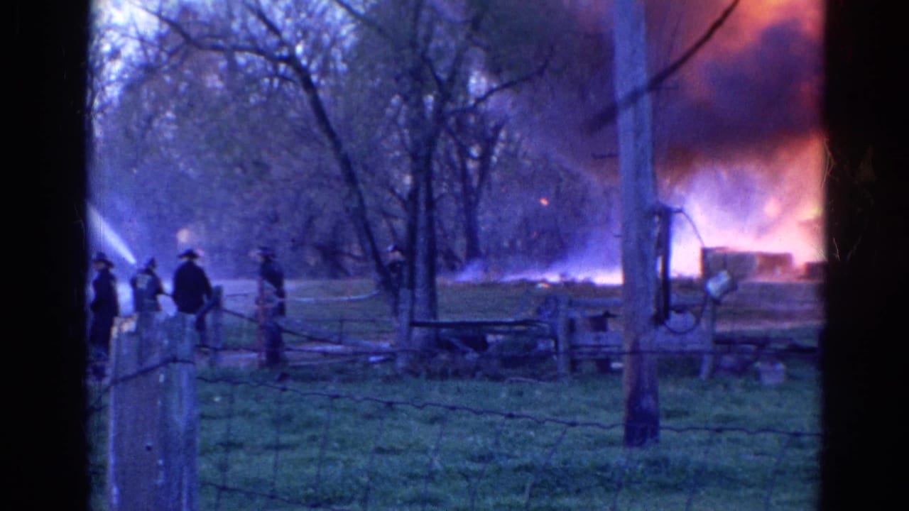 Firefighters and hose lines are visible near a rural field fire in Wauconda, Illinois, with smoke rising behind trees.