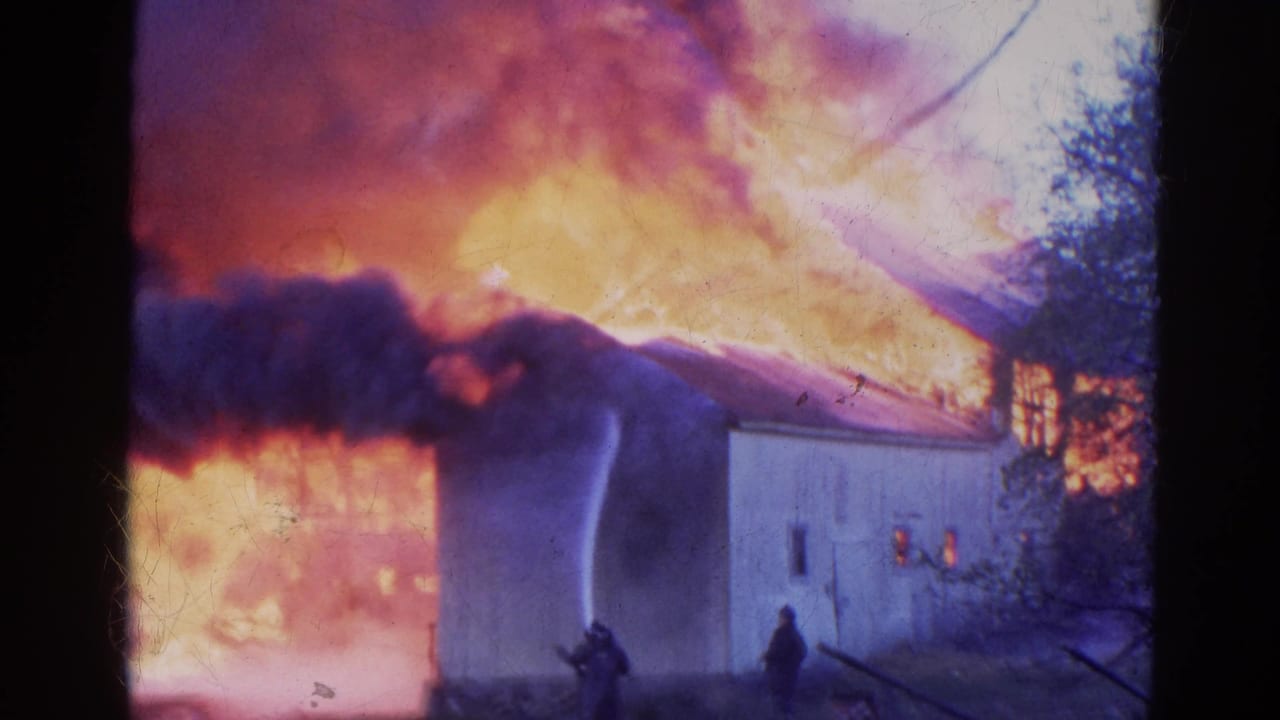 Firefighters near a building engulfed by flames and dark smoke.
