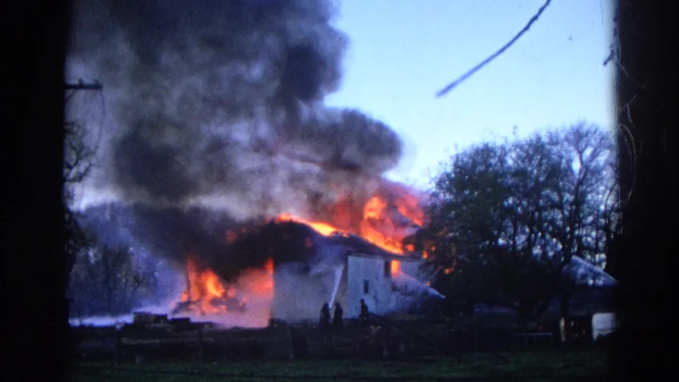 1968 Wauconda, Illinois 8mm frame showing a house engulfed by flames, dense smoke, firefighters, and hose spray.
