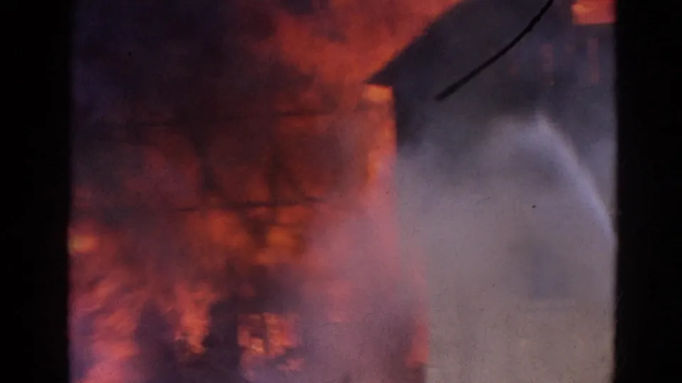 1968 Wauconda warehouse fire footage showing orange flames, smoke, and a pale hose stream through soft 8mm framing.
