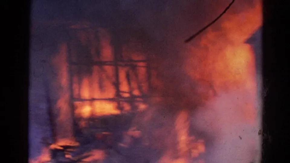 Burning warehouse structure in Wauconda, Illinois, with flames, smoke, and firefighting water spray visible in 8mm color footage.