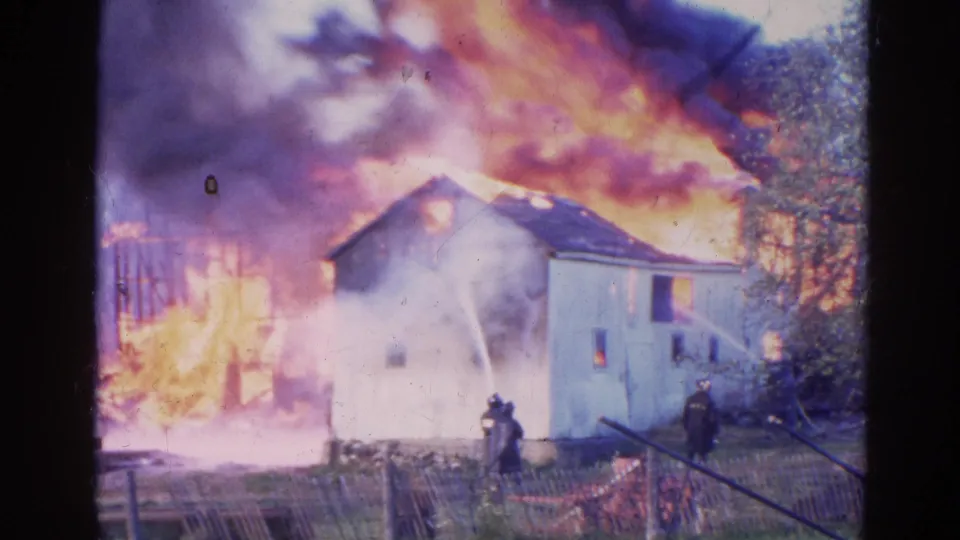 1968 Wauconda, Illinois 8mm frame with hose water striking a smoke-covered house during an active residential fire.