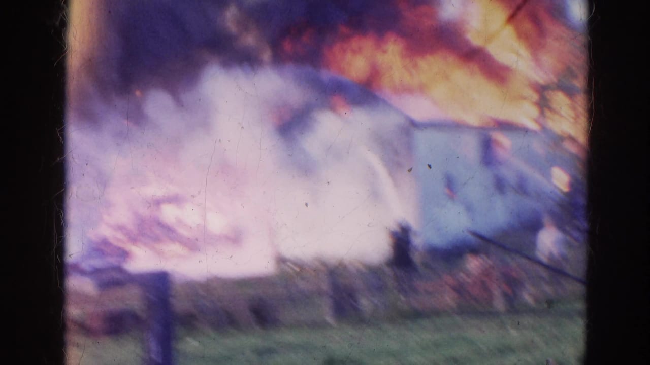 Bright flames and smoke obscure much of a burning white building.