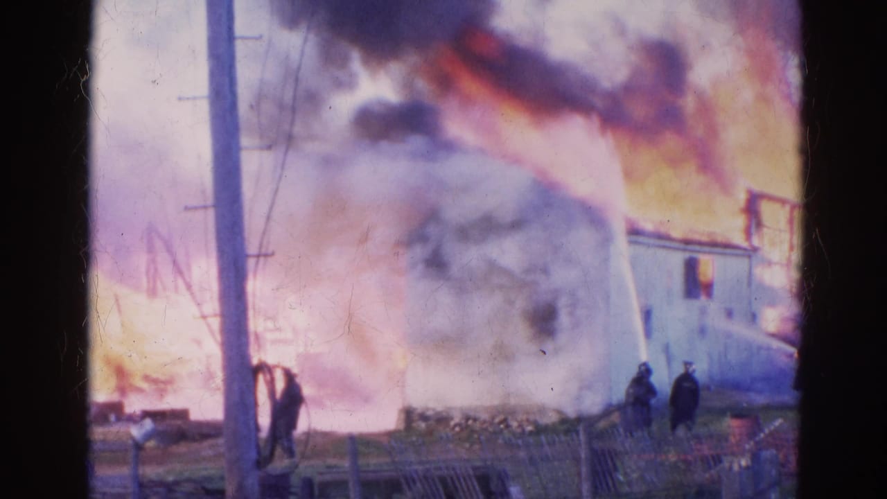 1968 Wauconda frame of dense smoke over a burning house, with firefighters and a water stream visible through the haze.