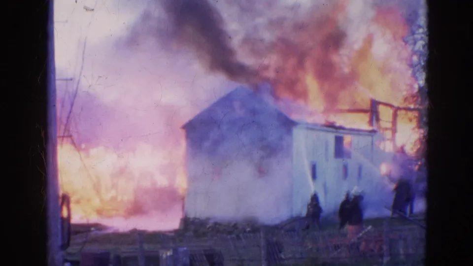 Wauconda, Illinois 1968 frame showing firefighters or trainees near hose lines as a white building burns heavily.