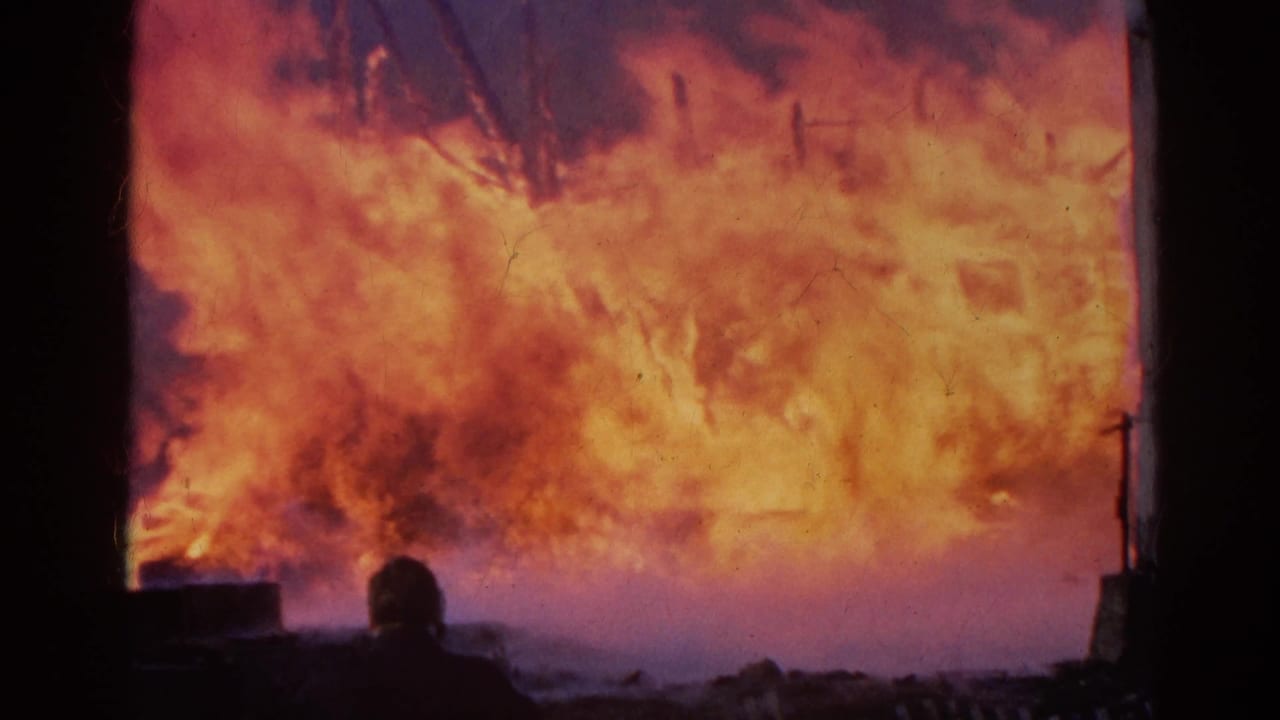 Large flames fill the background while a dark silhouetted figure stands in the foreground.