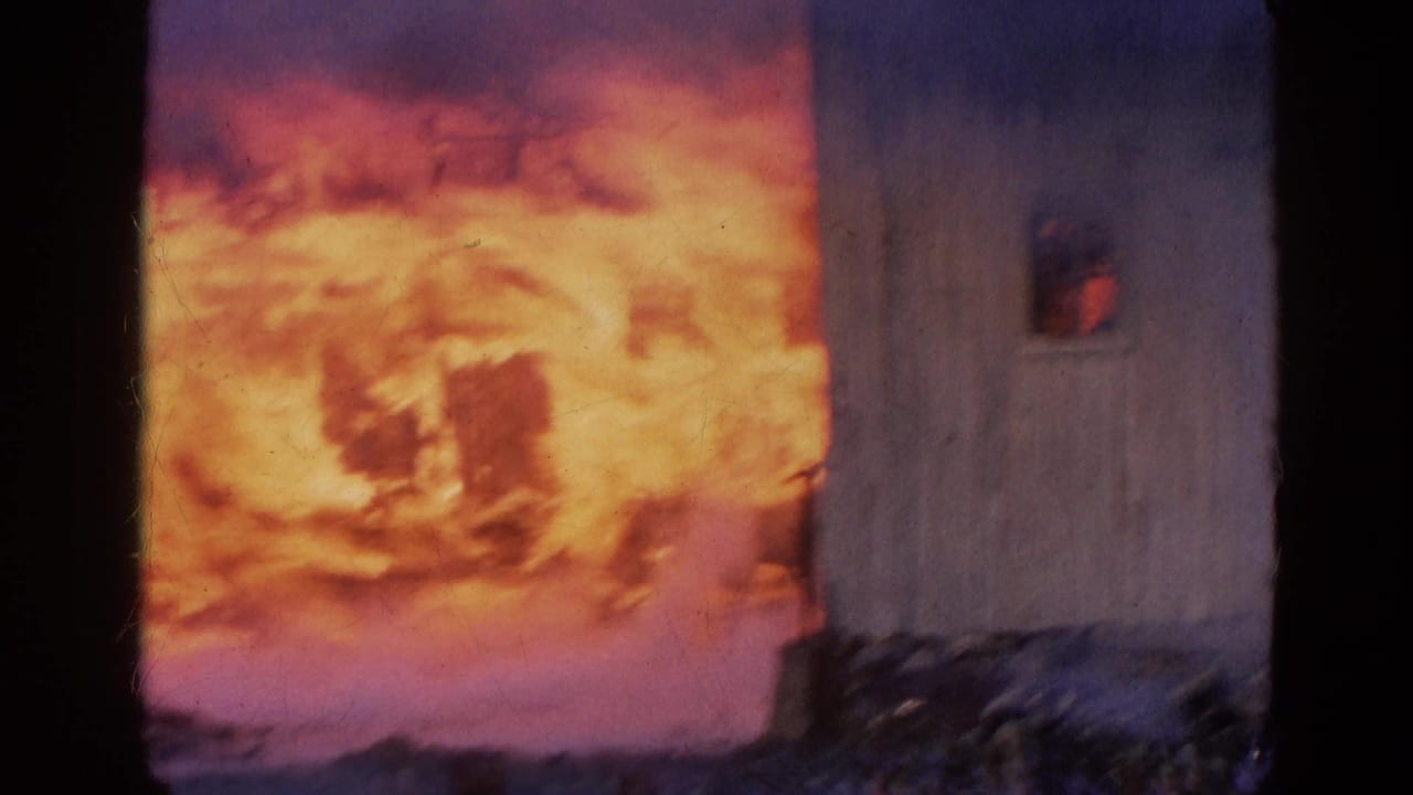 Large orange flames fill the left side beside a darkened structure and film border.