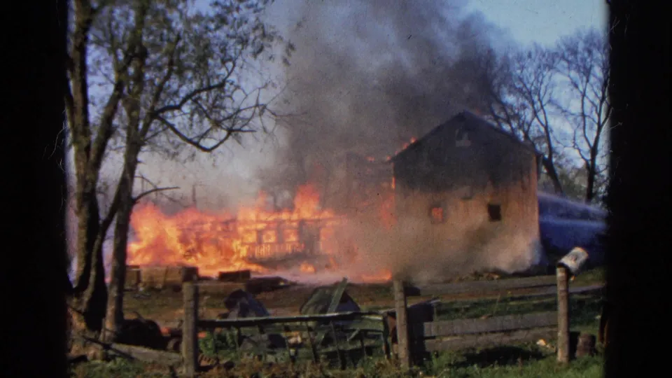 Final frame shows flames and smoke behind a fence near a rural building in Wauconda, Illinois 1968 footage.